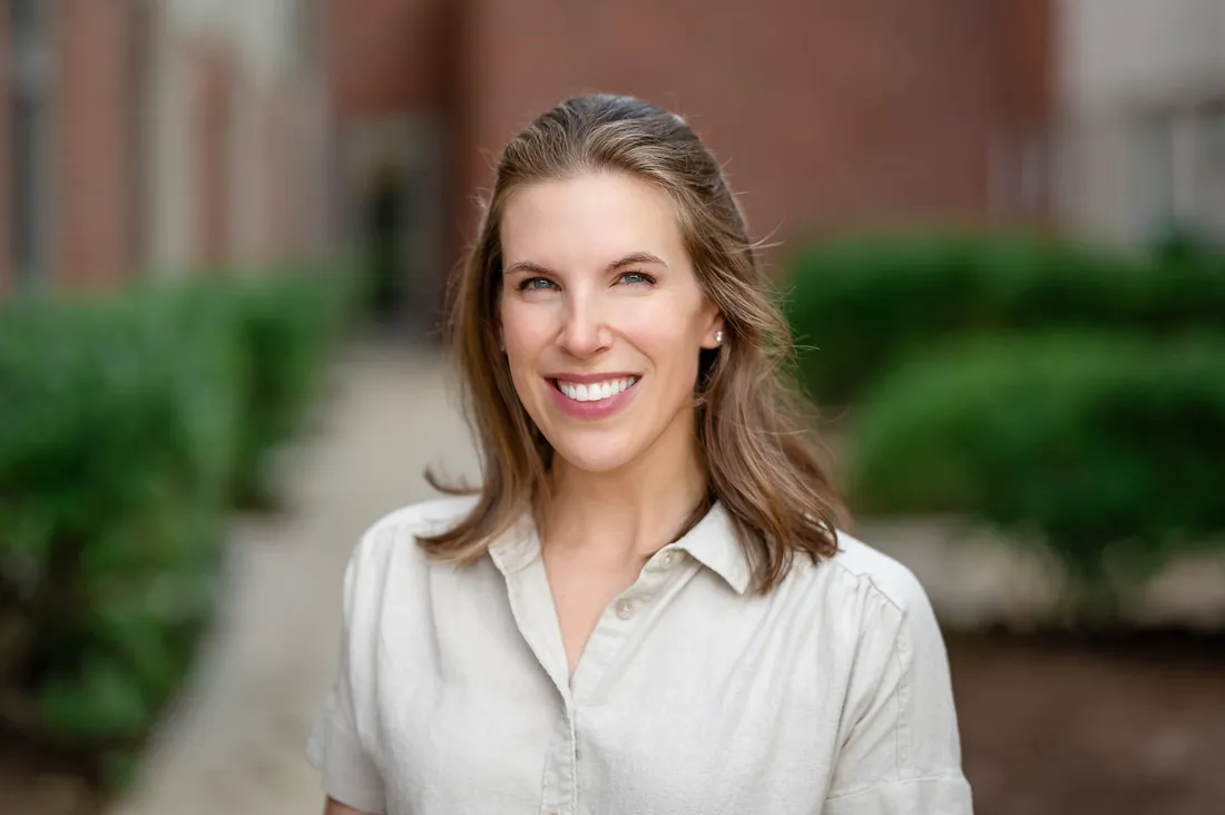 Lauren, smiling, outdoors in front of a brick building